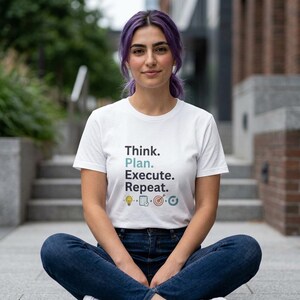May include: White t-shirt with the text "Think. Plan. Execute. Repeat." in black and teal. The shirt features small graphic icons below the text. The person in the image is wearing blue jeans.