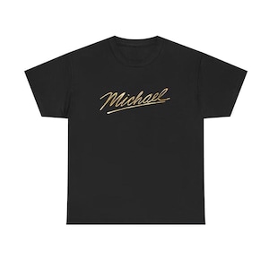 Op de afbeelding: Zwart T-shirt met de naam "Michael" in gouden letters op de borst. De tekst is in cursief geschreven. Het T-shirt heeft een ronde hals en is gemaakt van een zacht materiaal.