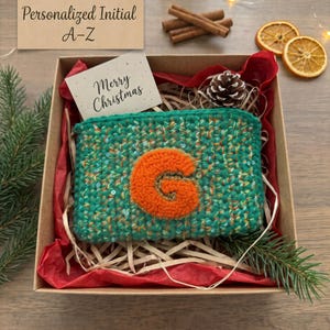 May include: A rectangular green crocheted pouch with a textured orange letter G appliqué, placed inside a cardboard gift box lined with red tissue paper. A card reads Merry Christmas and Personalized Initial A-Z.