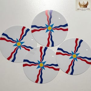 May include: Four white, circular ornaments with a design featuring red, blue, and yellow accents. Each ornament has a central starburst design with wavy lines radiating outwards. A small hole is at the top of each ornament.