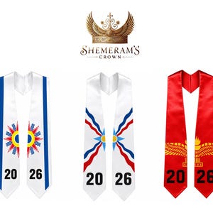 May include: Three white graduation stoles with the year 2026 printed on them. One has blue stripes and a sunburst design, another has red and blue accents, and the third is red with gold detailing.