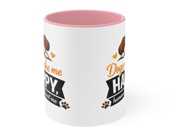 May include: A white ceramic mug with a pink interior and rim. The exterior features a graphic of a brown dog, orange hearts, and black paw prints. The text reads: Dogs make me HAPPY, humans not so much. The design is repeated on the mug surface.