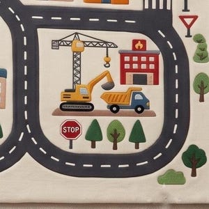 May include: A cream-colored play mat featuring a printed city map with dark gray roads, a yellow construction crane, a yellow excavator, a blue dump truck, a red fire station, green trees, and a red octagonal stop sign with white text.