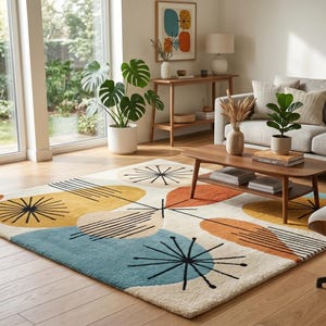 May include: A mid-century modern style area rug with a cream background and colorful geometric shapes in yellow, orange, and blue. Black lines radiate from the center of the shapes. The rug is in a living room with a sofa, chair, and coffee table.