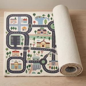 May include: A rectangular area rug featuring a printed city map with gray roads, a parking lot, green trees, and various buildings including a school with the text SCHOOL. The design includes stop signs, traffic lights, and a blue bus.