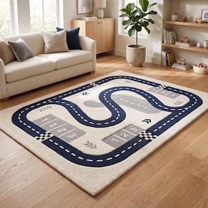 May include: A rectangular area rug with a cream-colored background featuring a dark blue winding road pattern. The design includes gray rectangular sections marked with the numbers 1, 2, and 3, along with black and white checkered finish lines.