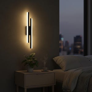 May include: A modern black and white wall sconce with a vertical design. The sconce has three parallel light bars that emit a warm, inviting glow. The fixture is mounted on a dark gray wall, creating a sleek and contemporary look.
