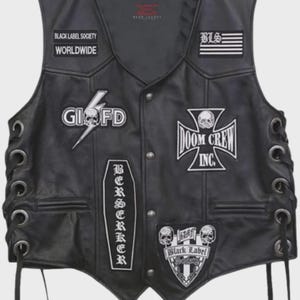 Op de afbeelding: Zwarte leren vest met meerdere patches, waaronder "BLACK LABEL SOCIETY WORLDWIDE", een schedel- en bliksemgrafiek en "DOOM CREW INC." Voorzien van veter aan de zijkant en een V-hals. Een kledingstuk in biker-stijl.