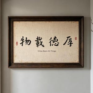 Puede incluir: Una pieza de arte mural rectangular con un marco de madera marrón oscuro y un lienzo texturizado de color beige claro. El centro muestra caracteres de caligrafía china en negro y el texto en inglés "Virtue Bears All Things" con dos sellos rojos.