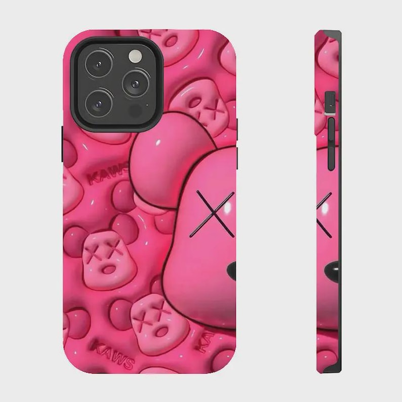 K&ouml;nnte beinhalten: Eine leuchtend pinke Smartphone-H&uuml;lle mit einem wiederkehrenden gepr&auml;gten Muster aus KAWS-Charakterk&ouml;pfen mit X-f&ouml;rmigen Augen und dem Schriftzug KAWS in Reliefoptik. Das Design umfasst einen schwarzen Kameraausschnitt und seitliche Tasten.