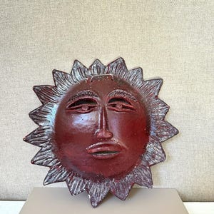 Vintage keramische wandsculptuur uit 1987 met een zonnegezicht, handgemaakt in een atelier, hemelse volkskunst.