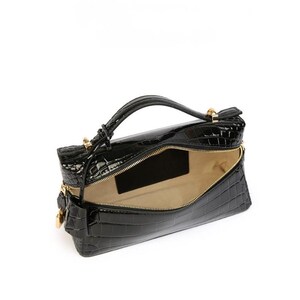 May include: A black handbag with a glossy, embossed crocodile skin texture. The bag features a structured rectangular shape, a single top handle, gold-toned metal hardware, and a wide zippered opening that reveals a light beige interior lining.
