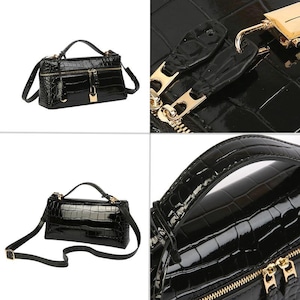 May include: A black handbag with a glossy crocodile-embossed texture, featuring a top handle, a detachable shoulder strap, gold-tone metal hardware, a zippered closure, and a small gold padlock attached to the front of the bag.