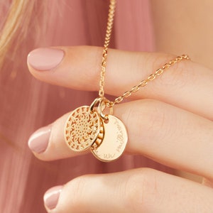 May include: Gold necklace with two charms. One charm is a delicate filigree design, the other is a round disc with the inscription "un million de fois".