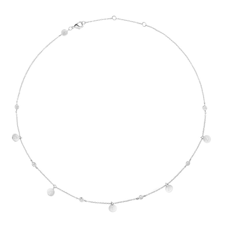 Puede incluir: Un collar de plata con una cadena delicada y peque&ntilde;os colgantes redondos. Los colgantes est&aacute;n espaciados uniformemente a lo largo de la cadena y tienen una superficie texturizada.