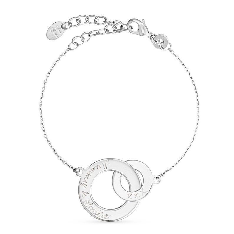 May include: Silver bracelet with two interlocking circles. The larger circle has the inscription "I love you" and the smaller circle has the inscription "xxx".