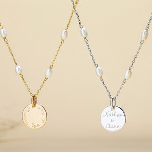 May include: Two delicate necklaces with pearl accents and personalized circular pendants. One pendant reads "I'm with you always, love" and the other reads "Nathan & Clara".
