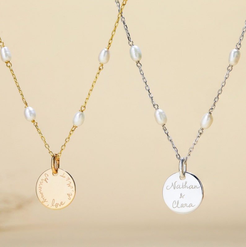 May include: Two delicate necklaces with pearl accents and personalized circular pendants. One pendant reads "I'm with you always, love" and the other reads "Nathan & Clara".