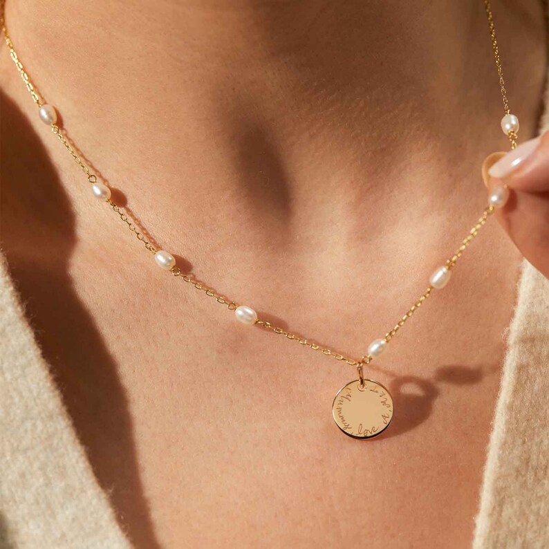 May include: A gold necklace with a delicate chain and small pearl accents. The necklace features a round pendant with the inscription "Love you to the moon and back".