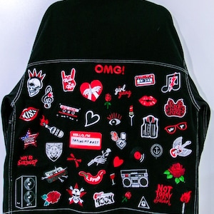 May include: A black denim jacket featuring numerous embroidered patches in red, white, and black. The patches include text like OMG!, girl gang, KISS, USA, WHY SO SERIOUS?, HELLO, I'M TRYING MY BEST, ROCK, and NOT TODAY Satan, alongside various icons.