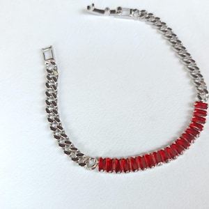 Puede incluir: Pulsera plateada con diseño de cadena de eslabones. La pulsera tiene una sección de gemas rectangulares rojas vibrantes. El cierre también es plateado. Esta joya es adecuada para el uso diario o para ocasiones especiales.