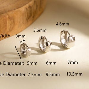 May include: Three silver hoop earrings of varying sizes. The smallest has a 3mm width, 5mm inside diameter, and 7.5mm outside diameter. The middle has a 3.6mm width, 6mm inside diameter, and 9.5mm outside diameter. The largest has a 4.6mm width, 7mm inside diameter, and 10.5mm outside diameter.