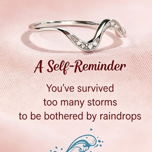 May include: A silver-toned wave-shaped ring featuring small embedded clear stones. The text reads: A Self-Reminder. You've survived too many storms to be bothered by raindrops. Below the text is a blue graphic illustration of a crashing ocean wave.