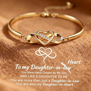 Op de afbeelding: Een goudkleurige armband met een centraal oneindigheidssymbool verweven met een hartvorm, geaccentueerd met kleine heldere steentjes. Onder de armband staat witte tekst: To my Daughter-in-law, You Were Hand Chosen by My Son, AND LIKE A DAUGHTER TO ME, You are more than just a Daughter-In-Law, You are also my Daughter-In-Heart.