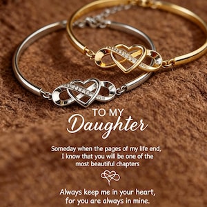 Puede incluir: Dos pulseras de metal, una dorada y otra plateada, cada una con un dije de corazón infinito incrustado con pequeñas piedras claras. El texto dice: TO MY Daughter, Someday when the pages of my life end, I know that you will be one of the most beautiful chapters. Always keep me in your heart, for you are always in mine.