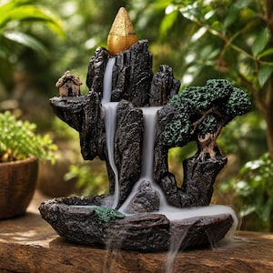 May include: A decorative tabletop waterfall fountain with a miniature landscape design. The fountain features a dark brown rock formation with a cascading waterfall effect, a small house, and a green tree. A gold-colored cone sits atop the rocks.