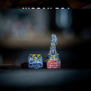 May include: Two decorative items: a small, stone-like cube with the number "33" in gold, and a trophy-shaped figurine. The figurine has a brick base, a silver upper portion, and the number "33" in gold. The word "EXPEDITION" is visible.