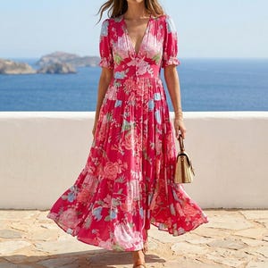 May include: A vibrant magenta maxi dress featuring a floral pattern in shades of pink, white, and light blue. The dress has a deep V-neckline, short puff sleeves, a button-down front, and a tiered skirt that flows to the ankles with a full silhouette.
