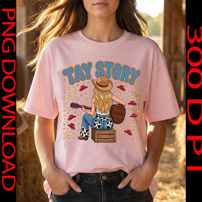 Pu&ograve; includere: Una t-shirt rosa chiaro con la grafica di una persona bionda che indossa un cappello da cowboy e jeans con stampa mucca, seduta su una cassa di legno mentre suona una chitarra acustica. Il testo TAY STORY &egrave; stampato sopra, circondato da stelle gialle e cappelli rossi.