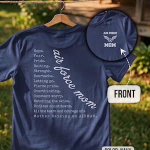 May include: A navy blue t-shirt featuring white text on the back listing emotional experiences like Hope, Fear, Pride, and Waiting, alongside the phrase air force mom. The front chest area displays a white Air Force Mom logo with wings.