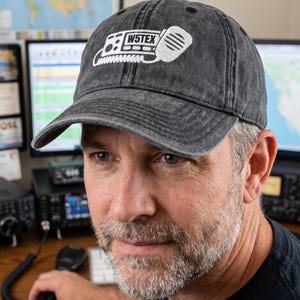 May include: A charcoal grey washed cotton baseball cap featuring an embroidered white graphic of a two-way radio transceiver with a handheld microphone. The text W5TEX is clearly visible in the center of the radio illustration on the front panel.