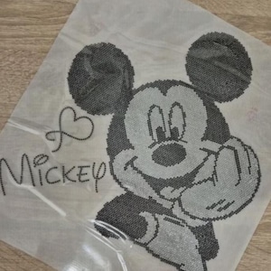 Könnte beinhalten: Ein Kreuzstichmuster mit Micky Maus in Schwarz und Grau. Das Design enthält das Wort "Mickey" mit einem Herzsymbol. Das Muster befindet sich auf einem durchscheinenden Blatt, wahrscheinlich zum Basteln.