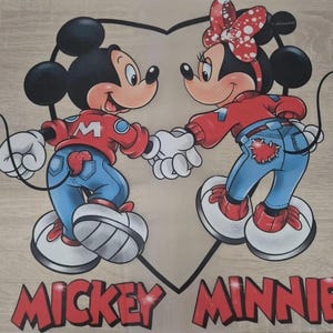 Op de afbeelding: Illustratie van Mickey en Minnie Mouse die elkaars hand vasthouden, tegen een hartvormige omtrek. Mickey draagt een rode jas, een blauwe spijkerbroek en witte handschoenen. Minnie draagt een rode strik met stippen, een rode jas en een blauwe spijkerbroek. De woorden "MICKEY MINNIE" staan onderaan.