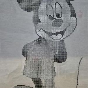 Könnte beinhalten: Ein schwarz-weißes Bild von Mickey Mouse, einer Zeichentrickfigur, wird in einem pixeligen Stil dargestellt. Die Figur lächelt und trägt Shorts. Das Bild befindet sich auf einem hellgrauen Hintergrund.