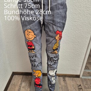Könnte beinhalten: Graue Hose in Jeansoptik mit Comicfiguren und dem Text "AVE YOUR DREAM". Die Hose hat einen Kordelzugbund und ist ca. 98 cm lang. Der Stoff ist 100% Viskose.