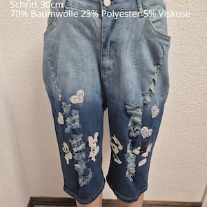 Könnte beinhalten: Blaue Jeans-Caprihose mit Distressed-Details und Strassverzierungen. Die Hose hat einen Knopfverschluss und Taschen. Der Text auf der Hose lautet: Einheitsgröße 44, Hosenbund 42-48cm, Länge 61cm, Schritt 30cm, 70% Baumwolle 23% Polyester 5% Viskose.