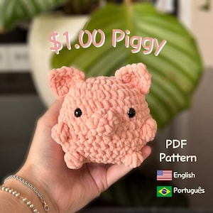 Pode incluir: Um porco de crochê rosa claro feito à mão, com olhos pretos e orelhas pequenas. A imagem inclui o texto "$1.00 Piggy" e "PDF Pattern" com bandeiras para inglês e português.