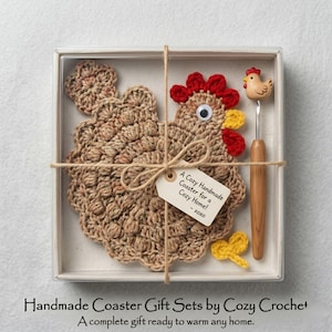 Può includere: Un set di sottobicchieri a forma di pollo all'uncinetto fatto a mano in una scatola trasparente. Il sottobicchiere è marrone con accenti rossi e gialli. Sono inclusi un uncinetto di legno con un piccolo pollo e un fiocco all'uncinetto giallo. L'etichetta recita "A Cozy Handmade Coaster for a Cozy Home! - xoxo".