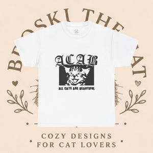 Puede incluir: Una camiseta blanca de manga corta con un estampado gráfico negro en el pecho. El diseño incluye el texto ACAB en una fuente gótica sobre un recuadro negro con la ilustración de un gatito y el texto ALL CATS ARE BEAUTIFUL debajo.