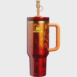 May include: A red and orange Stanley tumbler featuring a floral pattern, a gold-toned rim, and a matching orange handle. The lid includes a straw topped with a gold-colored pineapple charm. The Stanley logo is printed in yellow on the front.
