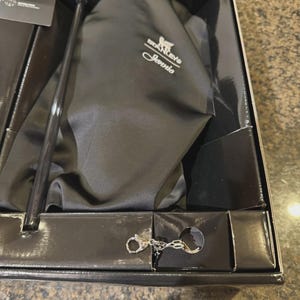 Puede incluir: Una bolsa de tela negra con el logotipo de Stanley y el nombre Jennie impresos en blanco, dentro de una caja negra. Incluye una pajita negra larga y un llavero de mosquet&oacute;n de metal plateado, junto con una peque&ntilde;a tarjeta informativa en el paquete.