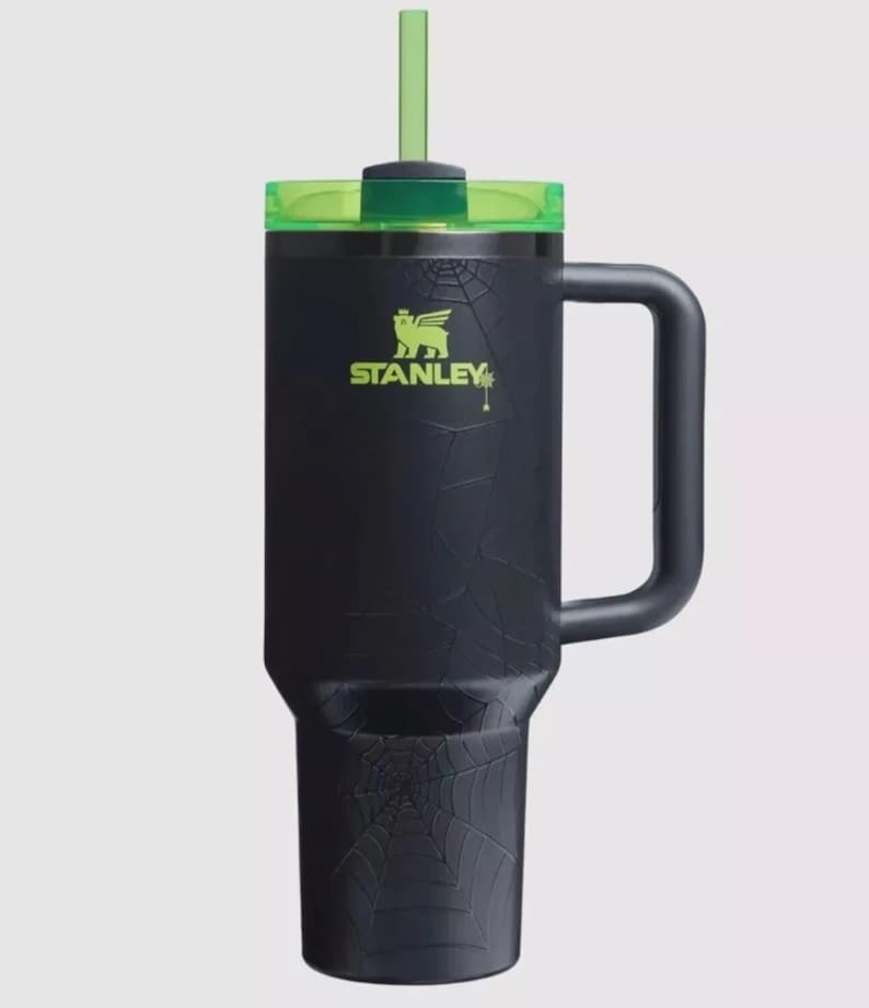 May include: A matte black insulated tumbler featuring a subtle embossed spiderweb pattern across the body. The cup includes a lime green translucent lid and a matching lime green straw. The Stanley logo is printed in lime green on the front.