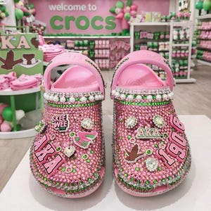 Diseño personalizado de zuecos Crocs con pedrería rosa y verde Jibbitz Tamaño 9 Fondo AI