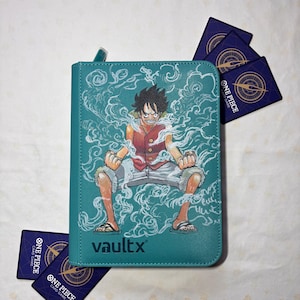 Puede incluir: Una carpeta con cremallera para cartas coleccionables de color verde azulado con un gráfico de Monkey D. Luffy de One Piece rodeado de efectos de humo blanco. El logotipo de VaultX está impreso en la parte inferior. Cuatro cartas azules de One Piece.