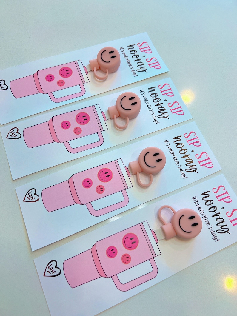 May include: Four pink tumblers with smiley face decals and a pink silicone lid with a smiley face. Each tumbler has a card attached with the text "Sip, Sip Hooray! It's Valentine's Day!"