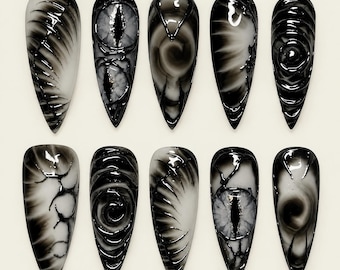 May include: A set of ten almond-shaped press-on nails featuring a monochromatic black and white color palette. The designs include intricate raised textures, swirling patterns, and detailed eye motifs with vertical pupils, all with a glossy finish.